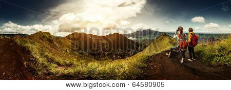 Two hikers with backpacks standing on top of the mountain enjoying valley view and taking a picture