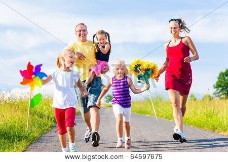 Family with three kids running down a hill in summer