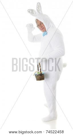 A senior male Easter bunny waving as he heads out to deliver an Easter basket.  On a white background.