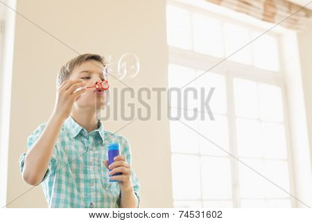 Boy blowing bubbles at home
