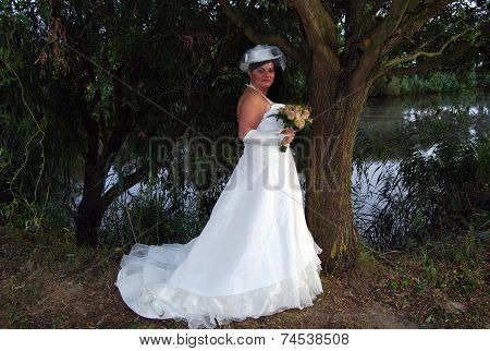 Young brunette overweight bride posing for the camera outdoors
