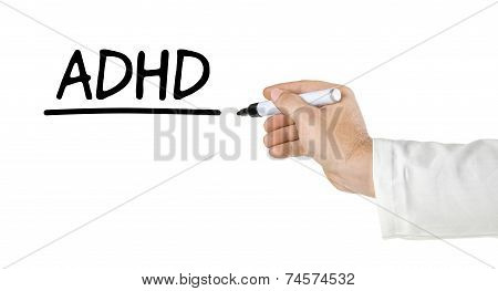 Hand with pen writing the word ADHD