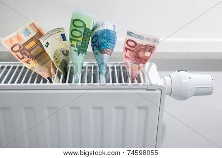 heating thermostat with money, expensive heating costs concept