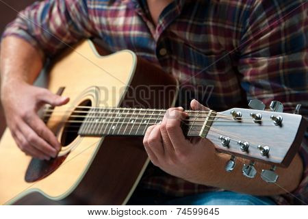 close up of a male musician playing acoustic guitar