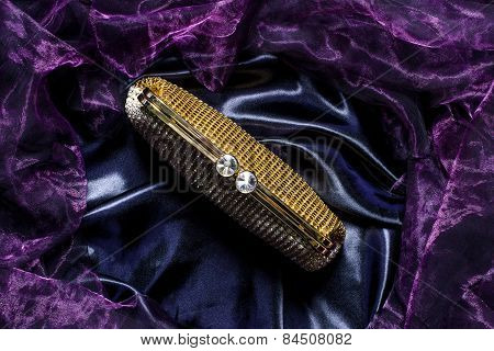 Golden Clutch With Diamonds On Silk Background
