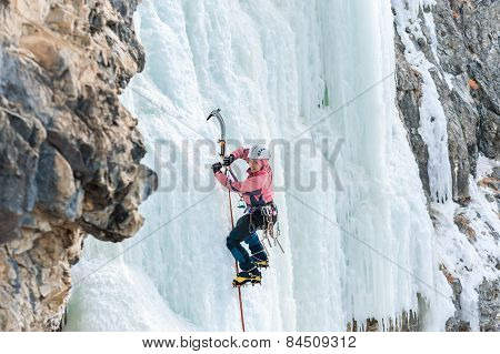 Girl Mountaineer Climbing A Frozen Waterfall And Smiling