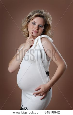 Attractive pregnant girl against beige background.
