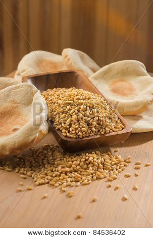 Whole wheat grains in wooden bowl with home made flat bread