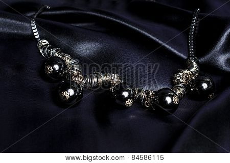 Necklace With Black Beads On Silk Background