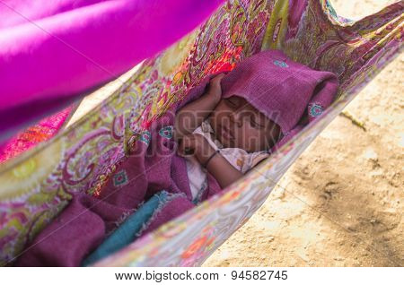 GODWAR, INDIA - 12 FEBRUARY 2015: Indian baby sleeps in makeshift crib made from blanket.