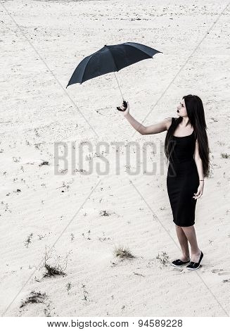 Young Woman With An Umbrella In A Desert