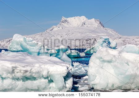 Huge Blue Icebergs Drifting And Laying Ashore With Sermitsiaq Mountain In The Background, Nearby Nuu