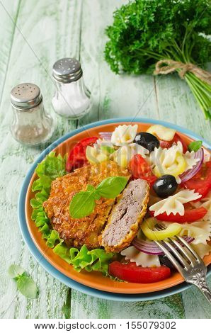 Cornflake crunchy pork cutlets served with pasta salad. Homemade cutlets on a wooden table in a rustic style