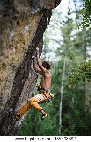 Rock climber falling down while ascending an overhanging. Extreme sport climbing.