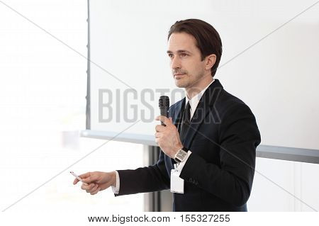 Speaker with microphone at business conference on whiteboard background