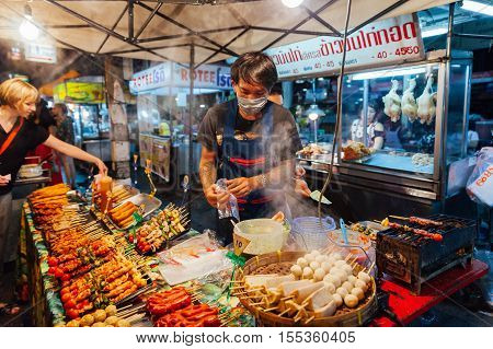 CHIANG MAI THAILAND - AUGUST 27: Young man sells satay at the Saturday Night Market on August 27 2016 in Chiang Mai Thailand.