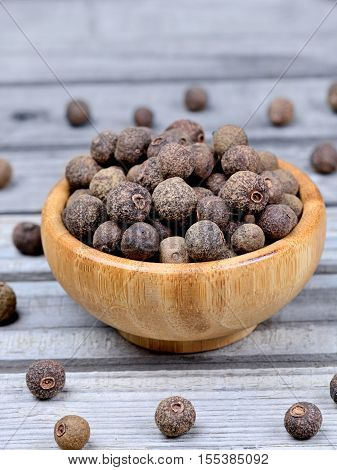 Bowl with allspice on grey wooden table