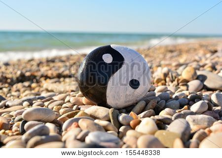 yin yang symbol painted on a rock on the sea beach