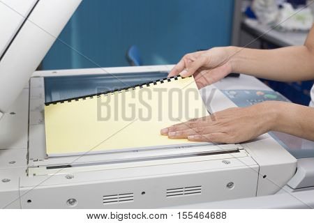 woman hands putting a sheet of paper into a copying device