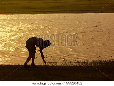 Girl picking up the shell behind the lighting silhouette.