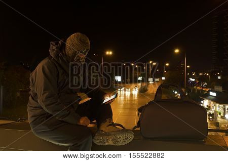 Terrorist in the center of a city sitting on a bridge. Night shot. Long exposure