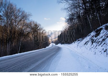 Lengthy descent of the winter road. Landscape with trees and hills.