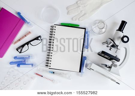 doctor workplace with microscope and blank open notebook at lab top view
