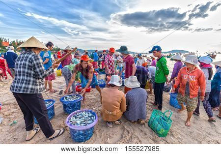 Phan Thiet, Vietnam - July 26th, 2016: Fish market session seas scene people gathered inside basket fish sale, strenuous rowing fishermen fish brought ashore fishing village in Phan Thiet, Vietnam