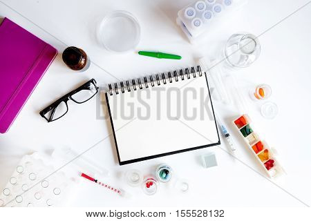 doctor workplace with blank open notebookat lab top view on white background