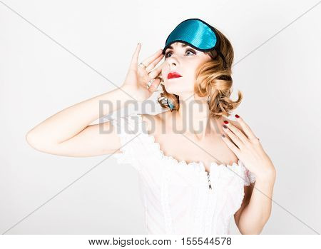 beautiful young woman in a pink dress and points for sleep, standing and posing. sleeping eye covering mask.