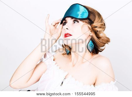 beautiful young woman in a pink dress and points for sleep, standing and posing. sleeping eye covering mask.