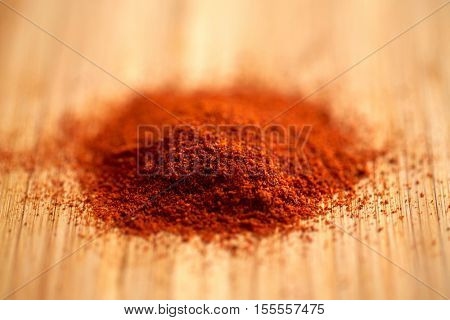 cooking, spice and ethnoscience concept - cayenne, chili pepper or paprika powder on wood
