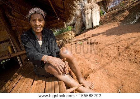 Mae Salong, Thailand - January 28, 2008 : 
In the province of Mae Salong, north of Thailand. 
An old woman from the Akha ethnic group rests in the shadow of her bamboo house
