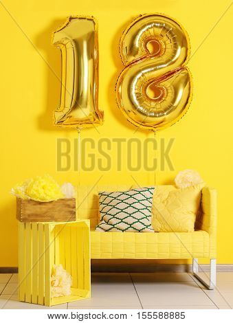 Golden balloons for 18th birthday celebration on yellow wall background