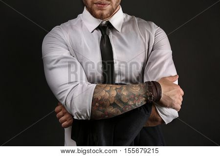 Young tattooed man posing on dark background
