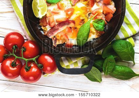 Pan Of Fried Eggs With Tomatoes, Bacon, Spinach, Lime
