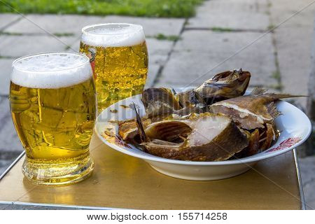 Two glasses of beer and snack plate with pieces smoked fish. Enjoing of tasty food.