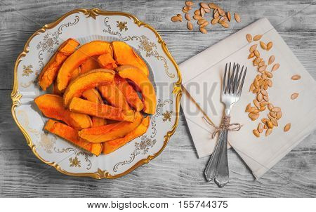 Halloween Baked pumpkin pieces on white vintage porcelain plate raw pumpkin pieces cut for baked napkin tissue pumpkin seeds on light white background wooden top view