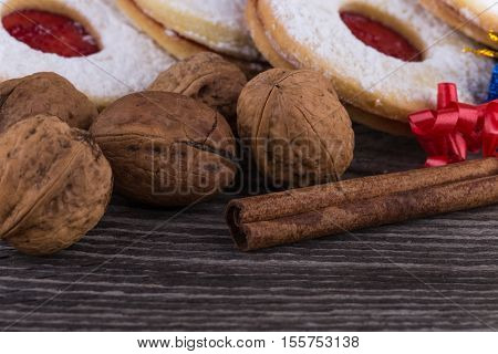 Homemade Christmas sweets with jam walnuts and cinnamon on old wooden surface.