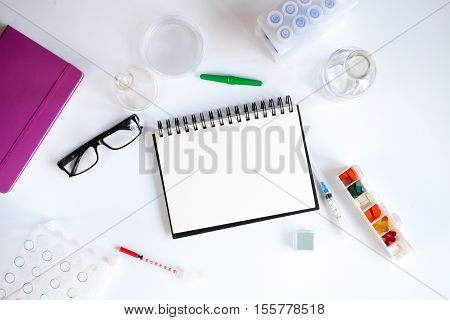 doctor workplace with blank open notebookat lab top view on white background