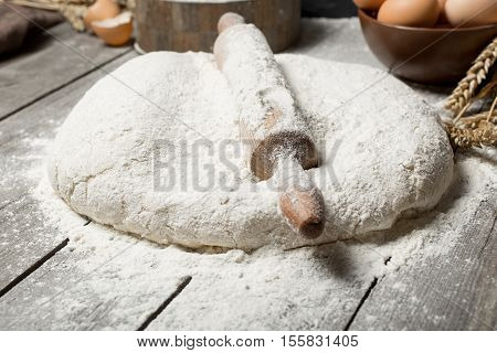 Rolling pin with flour close up on wooden table in bakery. Bakery background