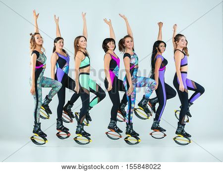 The group of young girls, jumping on kangoo training on gray