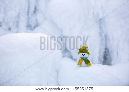 Incredible beautiful interesting white snow froze in strange textures forms and snowflakes and among all this beauty there is a little snowman in a hat and scarf.