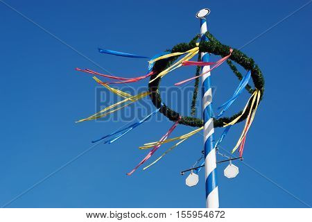 traditional multi colored bavarian maypole against blue sky