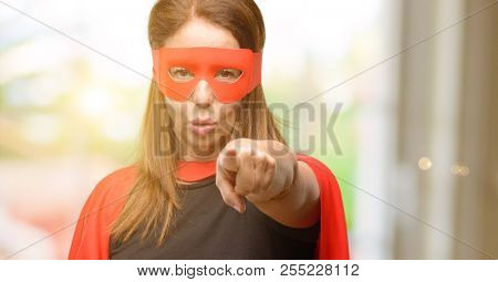 Middle age super hero woman wearing red mask and cape pointing to the front with finger