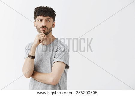 Waist-up Shot Of Creative Thoughtful Intrigued Good-looking Guy With Beard Holding Hand On Chin Turn