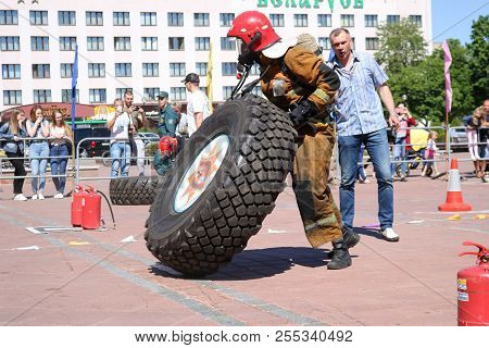 A Fireman In A Fireproof Suit And A Helmet Runs And Turns A Large Rubber Wheel In A Fire Fighting Co