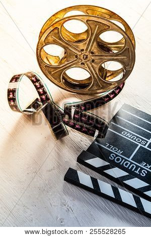 Vintage film claper with film reel placed on wood. Filmammakers equipment background