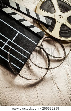Vintage film claper with film reel placed on wood. Filmammakers equipment background