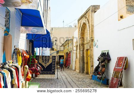 Sousse, Tunisia - August 28, 2015: The Clothes And Rug Stores Around The Medieval Gateway Of Zaouia 